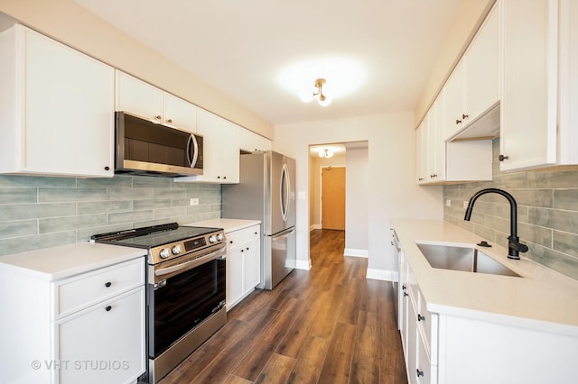 kitchen with baseboards, dark wood-style floors, tasteful backsplash, a sink, and stainless steel appliances