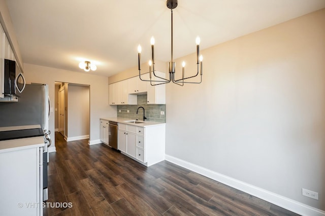 kitchen featuring decorative backsplash, appliances with stainless steel finishes, baseboards, white cabinets, and a notable chandelier