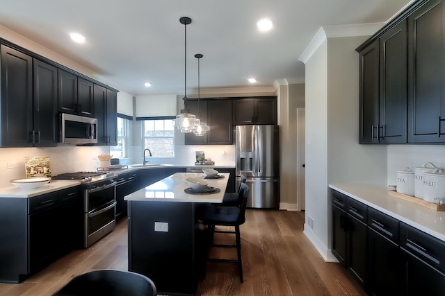 kitchen featuring a kitchen breakfast bar, appliances with stainless steel finishes, light countertops, and a sink
