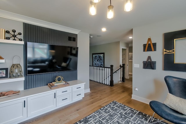 living room featuring visible vents, light wood-style flooring, and baseboards