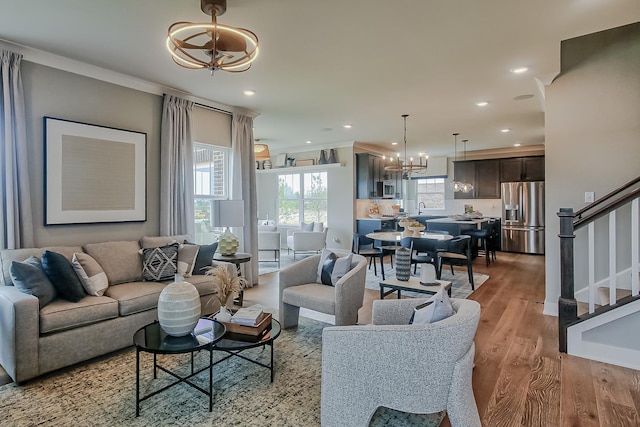 living area featuring recessed lighting, an inviting chandelier, stairway, and light wood-style floors