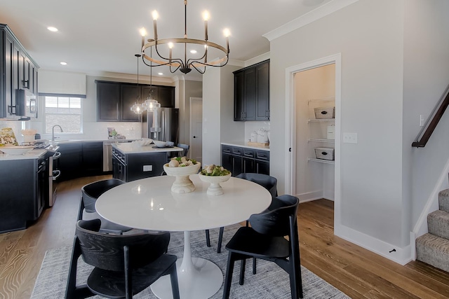 dining area with recessed lighting, wood finished floors, ornamental molding, stairway, and a notable chandelier