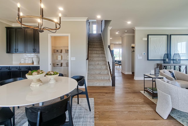 dining area with stairs, ornamental molding, light wood finished floors, baseboards, and a notable chandelier