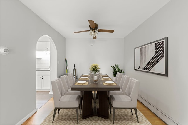 1056 N Mill St Unit 306, Naperville, IL 60563 - dining room featuring baseboard heating, a ceiling fan, light wood finished floors, and arched walkways