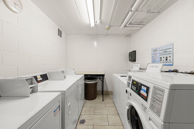 1056 N Mill St Unit 306, Naperville, IL 60563 - community laundry room featuring washing machine and clothes dryer, concrete block wall, and light tile patterned flooring