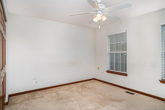 carpeted spare room with baseboards, a ceiling fan, and visible vents