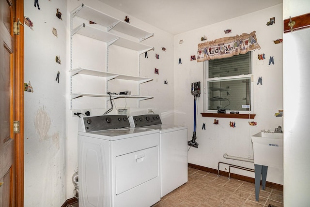 clothes washing area with baseboards, laundry area, and washing machine and dryer