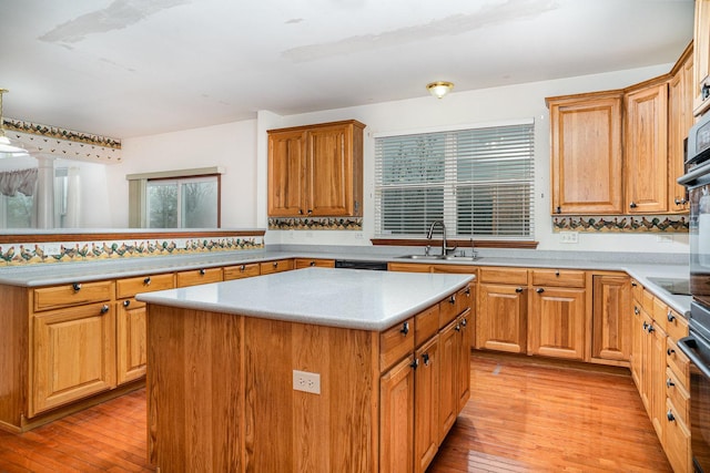 kitchen featuring a center island, light countertops, a sink, light wood finished floors, and dishwasher