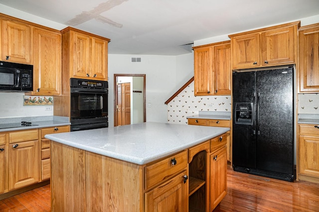 kitchen with light countertops, black appliances, light wood finished floors, and visible vents