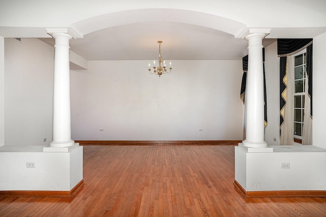 interior space featuring baseboards, decorative columns, and hardwood / wood-style floors