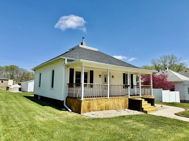 view of front facade featuring covered porch, a shingled roof, and a front yard