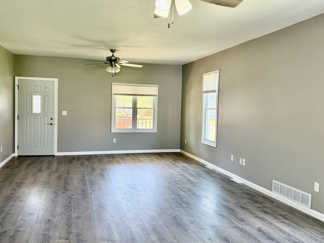 empty room featuring visible vents, baseboards, ceiling fan, and dark wood finished floors