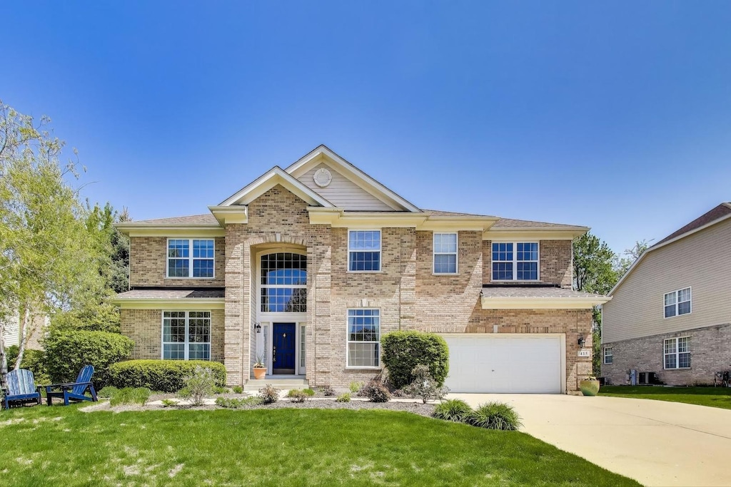 415 Lela Ln, Bartlett, IL 60103 - traditional home with concrete driveway, a garage, a front lawn, brick siding, and central AC