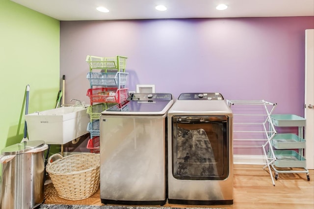 clothes washing area featuring washing machine and dryer, wood finished floors, and recessed lighting