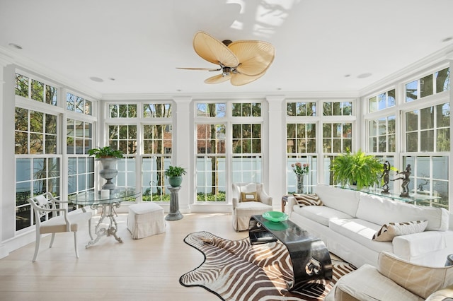 sunroom / solarium featuring ornamental molding, wood finished floors, ornate columns, and floor to ceiling windows