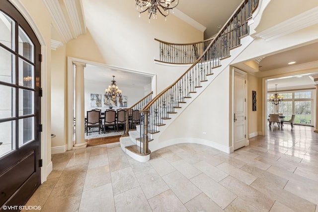 entrance foyer with crown molding, stairway, baseboards, an inviting chandelier, and ornate columns