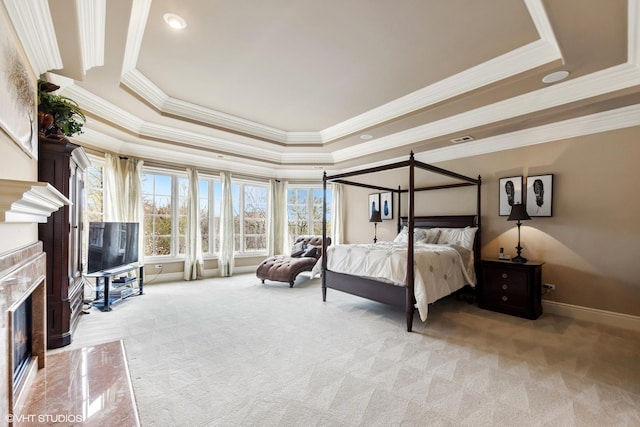 bedroom featuring visible vents, a tray ceiling, carpet floors, ornamental molding, and a fireplace