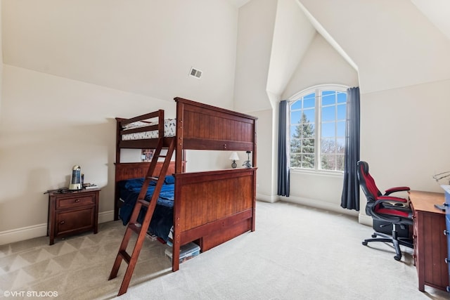 bedroom with baseboards, visible vents, light colored carpet, and high vaulted ceiling