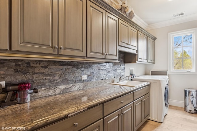 laundry area with independent washer and dryer, cabinet space, a sink, visible vents, and crown molding