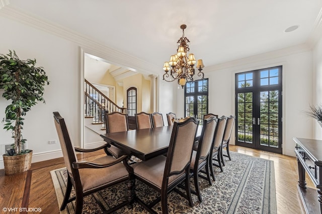 dining area with crown molding, light wood finished floors, stairs, and a chandelier