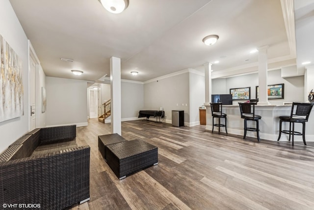 living area featuring stairway, crown molding, baseboards, indoor bar, and wood finished floors