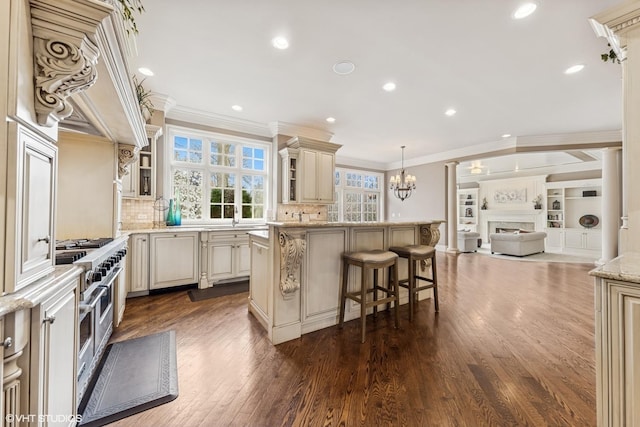 kitchen featuring range with two ovens, open floor plan, cream cabinets, and crown molding