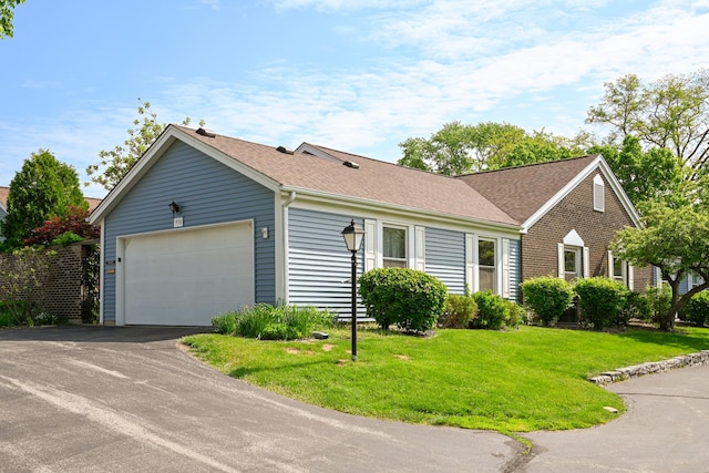 ranch-style home with a garage, asphalt driveway, a front yard, and a shingled roof