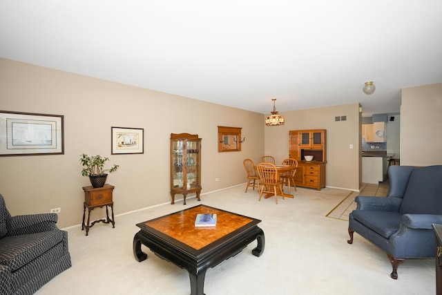 living room featuring light colored carpet, baseboards, and a chandelier