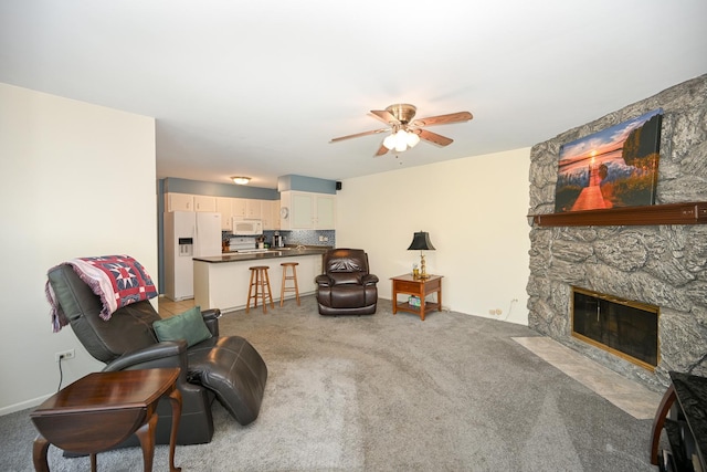 living room with ceiling fan, light carpet, and a stone fireplace