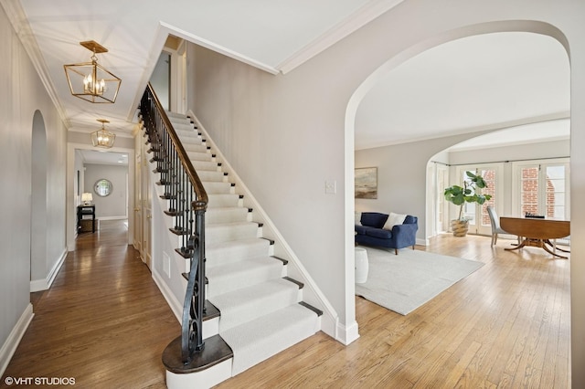 495 Willow Rd, Winnetka, IL 60093 - stairway featuring arched walkways, wood finished floors, ornamental molding, a chandelier, and baseboards