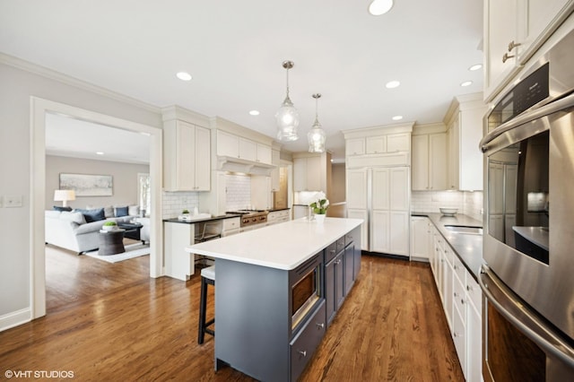 495 Willow Rd, Winnetka, IL 60093 - kitchen featuring appliances with stainless steel finishes, backsplash, a kitchen breakfast bar, recessed lighting, and dark wood-style floors