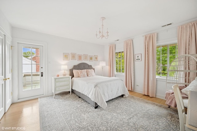 495 Willow Rd, Winnetka, IL 60093 - bedroom with access to exterior, multiple windows, light wood finished floors, and a chandelier
