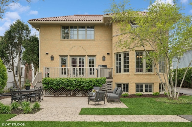 495 Willow Rd, Winnetka, IL 60093 - rear view of house featuring a tile roof, a lawn, a patio, and brick siding