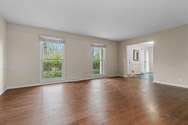 unfurnished living room with baseboards, visible vents, and wood finished floors