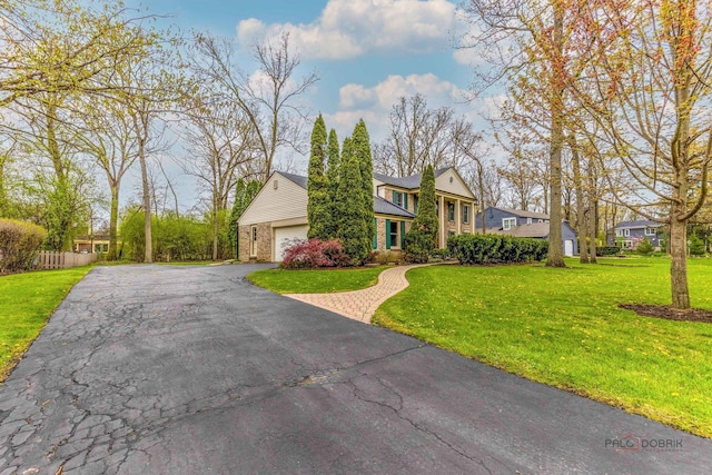 view of front of home featuring fence, a front lawn, brick siding, a garage, and driveway
