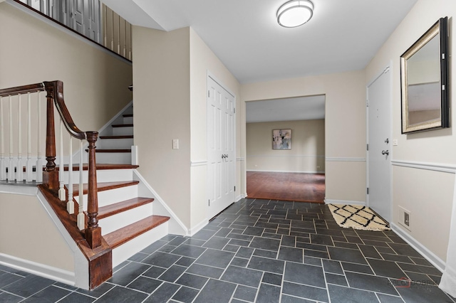 foyer entrance featuring visible vents, baseboards, and stairway
