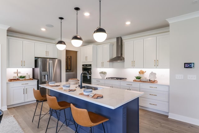 kitchen featuring a sink, decorative backsplash, a kitchen breakfast bar, wall chimney range hood, and appliances with stainless steel finishes