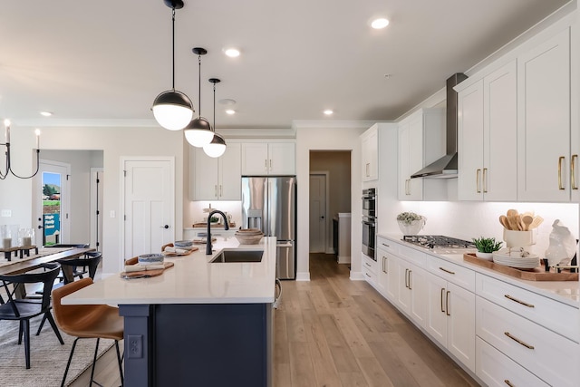 kitchen featuring stainless steel appliances, a sink, ornamental molding, and wall chimney range hood