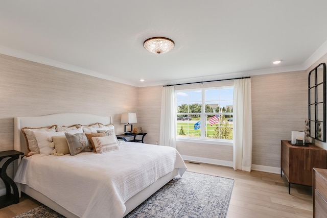 bedroom featuring baseboards, crown molding, and light wood finished floors