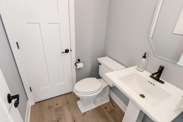 half bath featuring toilet, a sink, and wood finished floors