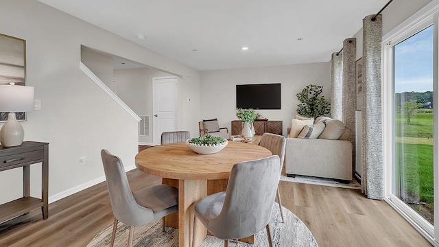 dining space with visible vents, light wood-style flooring, stairs, and baseboards