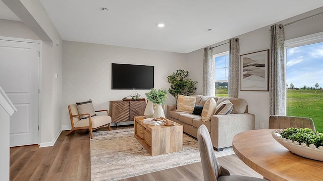 living room featuring recessed lighting, an accent wall, light wood-style flooring, and baseboards