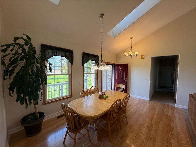 17N975 Harmony Rd, Hampshire, IL 60140 - dining area featuring a skylight, wood finished floors, baseboards, high vaulted ceiling, and a notable chandelier