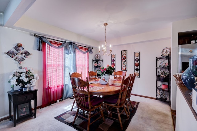 dining space with baseboards, a notable chandelier, and light carpet