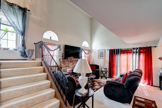 living room featuring a healthy amount of sunlight, carpet floors, high vaulted ceiling, and stairs