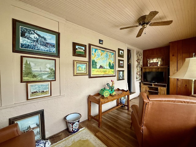 living area with wooden ceiling, wood finished floors, a fireplace, a textured wall, and a ceiling fan