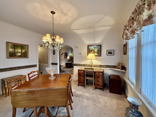 dining space with a chandelier, arched walkways, light carpet, and ornamental molding