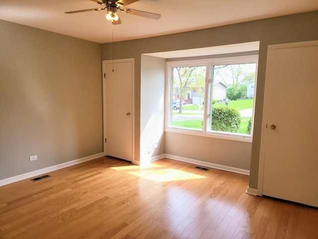 spare room featuring a ceiling fan, baseboards, visible vents, and light wood finished floors