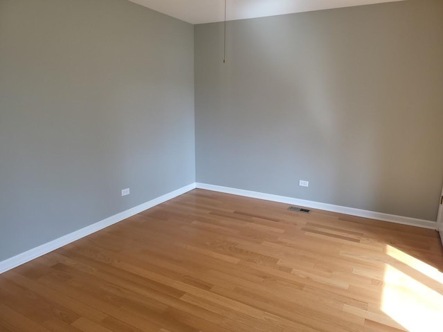 unfurnished room featuring baseboards, visible vents, and light wood-type flooring