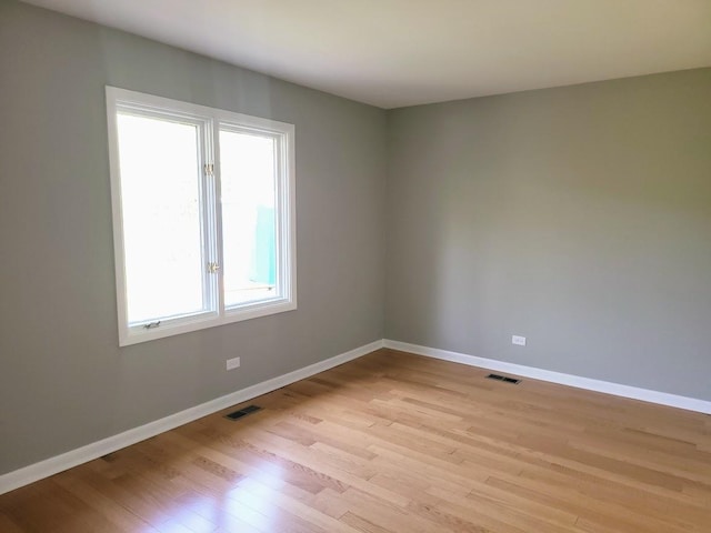 unfurnished room with baseboards, light wood-style flooring, and visible vents
